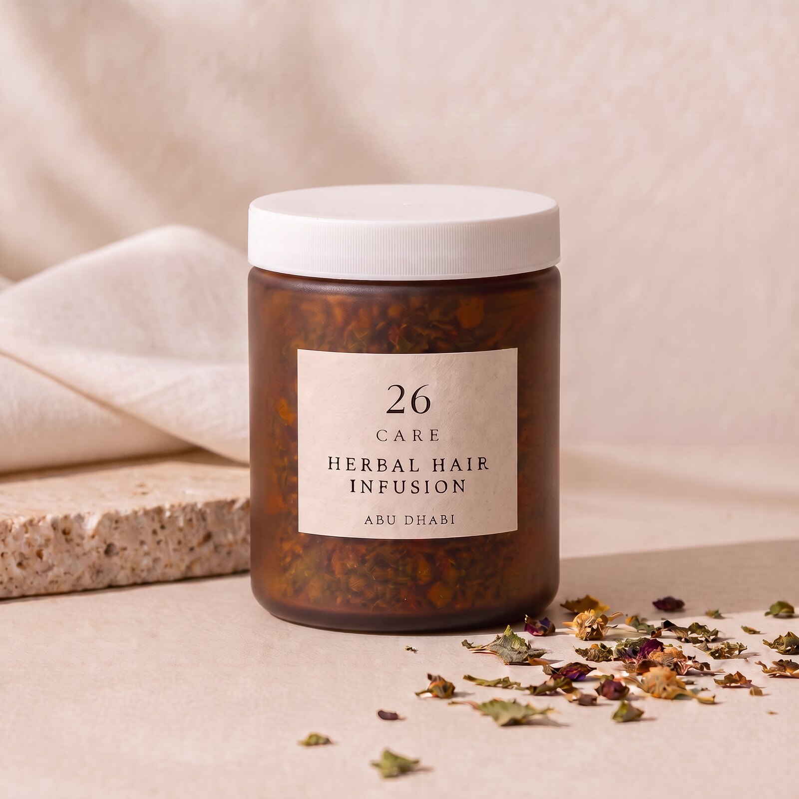 26 Care Herbal Hair Infusion in a frosted amber jar with loose dried botanicals beside it — Front — lid closed
